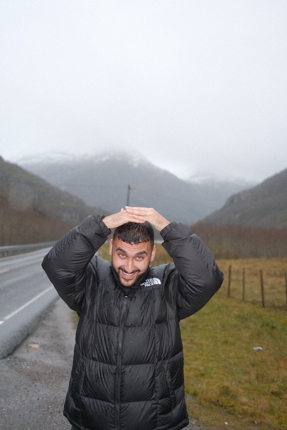 Abdalla in the rain with his hands on his head, pulling a face